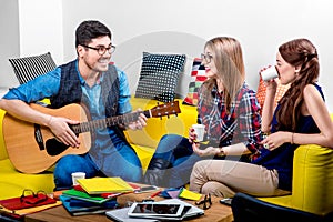 Man playing a guitar with girlfriends