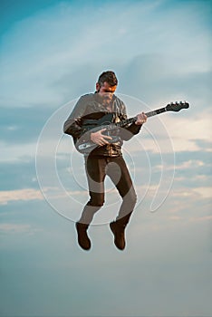Man playing guitar at sky background. Freedom and creativity concept
