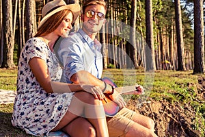 Man playing guitar to his girl on a picnic.