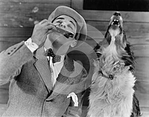 Man playing harmonica with howling dog photo