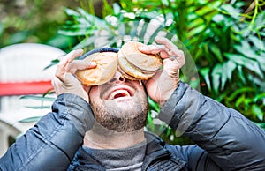 Man playing with his food - placing his hamburgers on his face