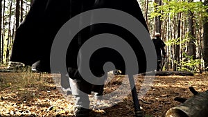 Man playing larp is wearing black cloak and walking through the forest