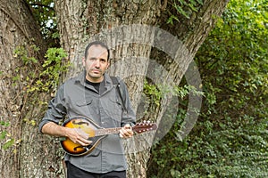 Man Playing Mandolin Against a Tree