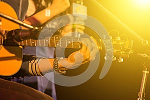 Man playing music by wooden acoustic guitar in the concert stage