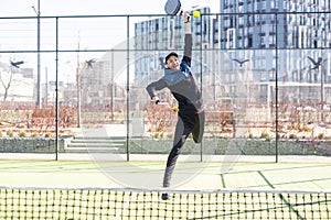 Man playing padel in a green grass padel court indoor behind the net