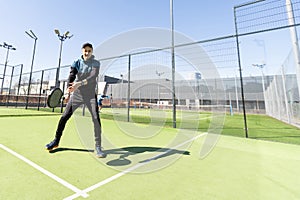 Man playing padel in a green grass padel court indoor behind the net