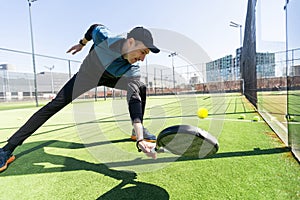 Man playing padel in a green grass padel court indoor behind the net