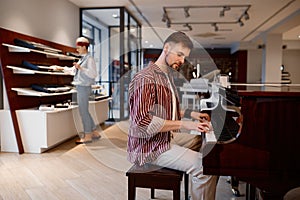 Man playing piano at music workshop while woman choosing electric synthesizer