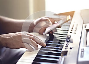 Man playing piano and using mobile phone. Person recording sound, reading notes from smartphone screen or writing lyrics.