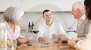 Man playing poker game with parents and wife in kitchen
