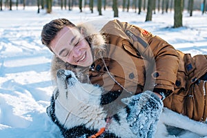 Man playing with siberian husky dog in snowy park