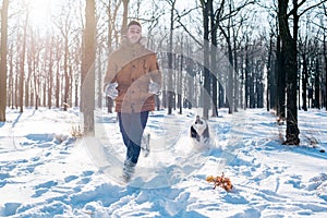 Man playing with siberian husky dog in snowy park