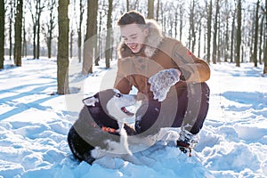 Man playing with siberian husky dog in snowy park