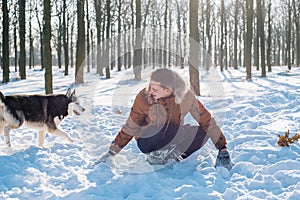 Man playing with siberian husky dog in snowy park