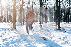 Man playing with siberian husky dog in snowy park