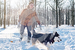 Man playing with siberian husky dog in snowy park