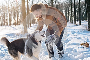 Man playing with siberian husky dog in snowy park