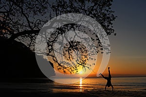 Man playing somersaults on the beach at sunset, red sky