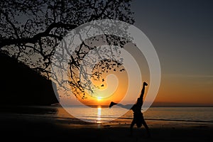 Man playing somersaults on the beach at sunset, red sky