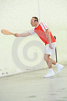 Man playing squash with wood racket