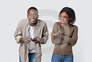 Man playing video games, woman is annoyed