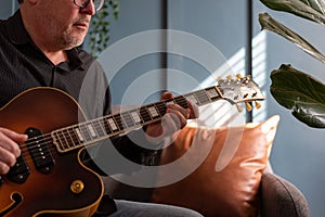 Man playing a vintage jazz guitar at home