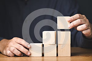 Man playing wooden cubes, career progress, build success