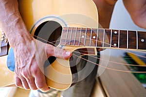 man plays acoustic guitar, close-up hands, strings hanging freely, guitar tuning, concept of creativity, guitar lessons, replacing