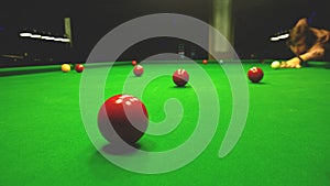 A man plays Billiards. Bright colorful balls to play snooker. Dim lights