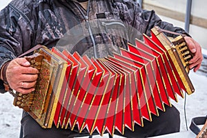 a man plays a bright harmonica on the street in winter, a street musician. An ancient musical instrument.