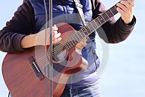 A man plays the guitar on the shore of the sea.