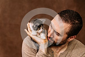man plays with a kitten. Hugs him and kisses him