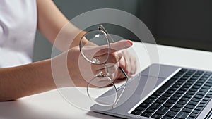 Man plays nervously with eyeglasses working at laptop