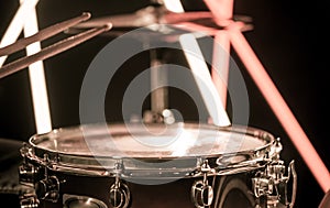 A man plays with sticks on a musical percussion instrument, close-up. On a blurred background of colored lights.