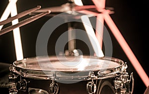 A man plays with sticks on a musical percussion instrument, close-up. On a blurred background of colored lights. photo