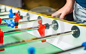 Man plays table football. Detail of man`s hands playing the kicker