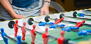 Man plays table football. Detail of man`s hands playing the kicker