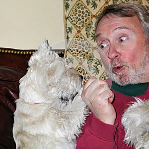 Man plays and talks with Westie dog with funny look on his face