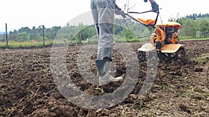 Man plowing field with cultivator, garden preparation