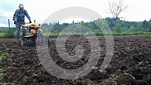 Man plowing field using a cultivator, garden preparation