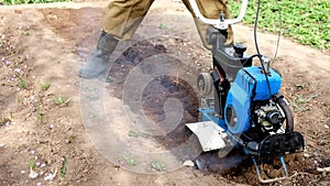 A man plows the ground with a cultivator