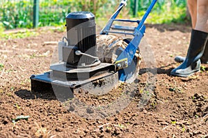 A man plows the ground in the garden with an electric cultivator photo