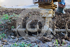 A man plows the ground with a tiller block in the garden