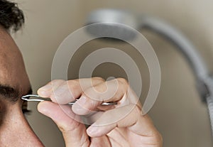 Man plucking his eyebrows with tweezers