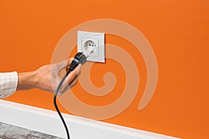 Man plugging cord into a electrical outlet