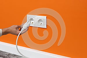 Man plugging cord into a electrical outlet