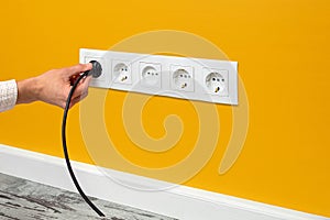 Man plugging cord into a electrical outlet