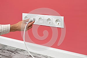 Man plugging cord into a electrical outlet