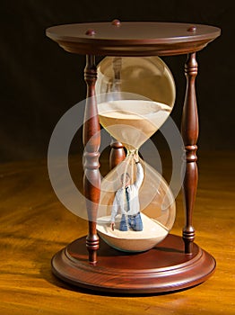 Man plugging hole inside hour glass trying to slow the flow of sand and stop time