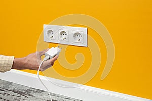 Man plugging phone adapter into a electrical outlet